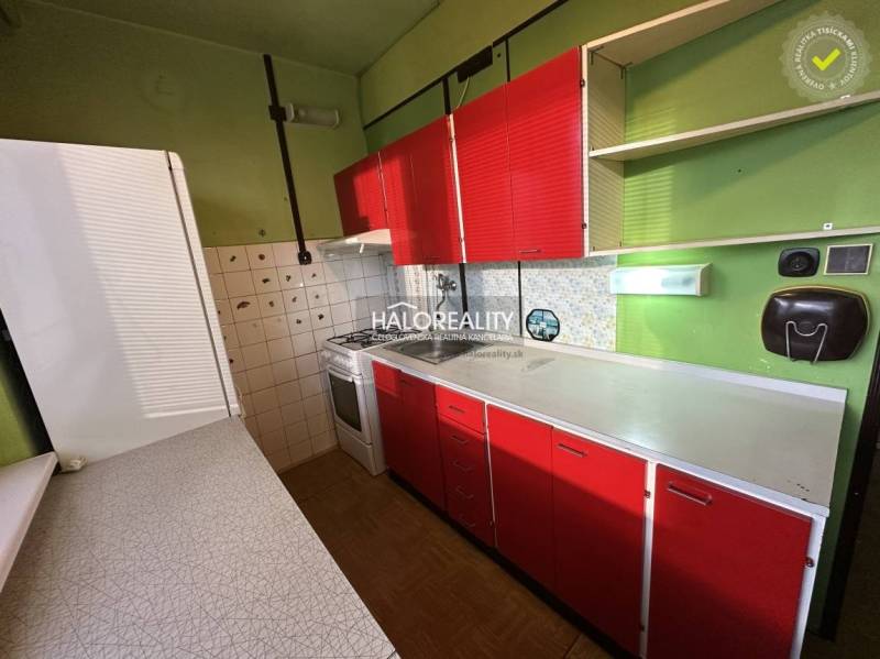 A kitchen in a 3-room apartment with green walls and red cabinets.