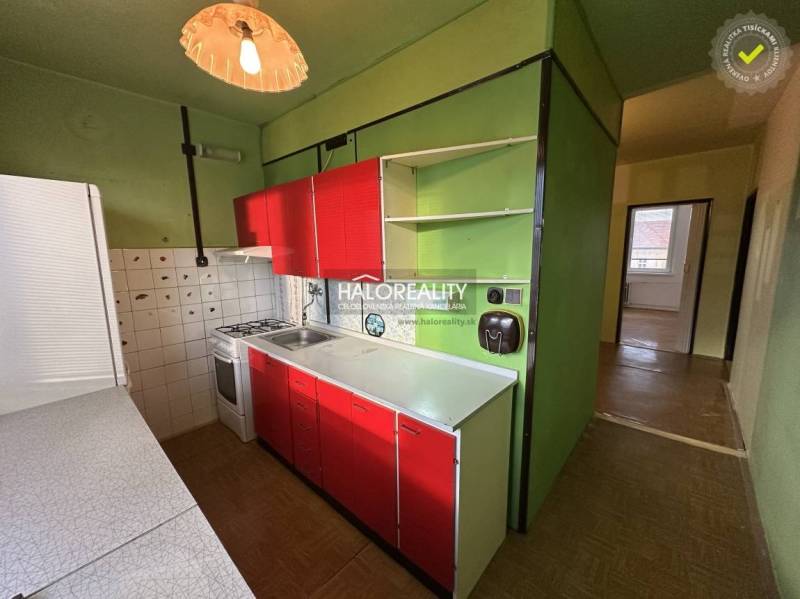 A kitchen in a 3-room apartment with green walls and red cabinets.