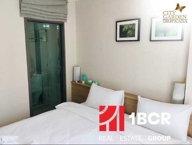 Interior of a 2-room apartment with a bed, decoration, and a built-in bathroom behind glass doors.