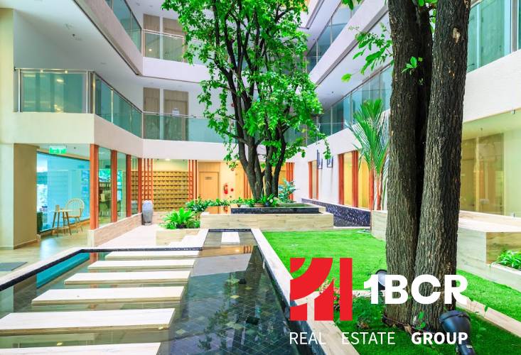 Construction of apartments with an indoor garden and water features, including elegant pathways and greenery.
