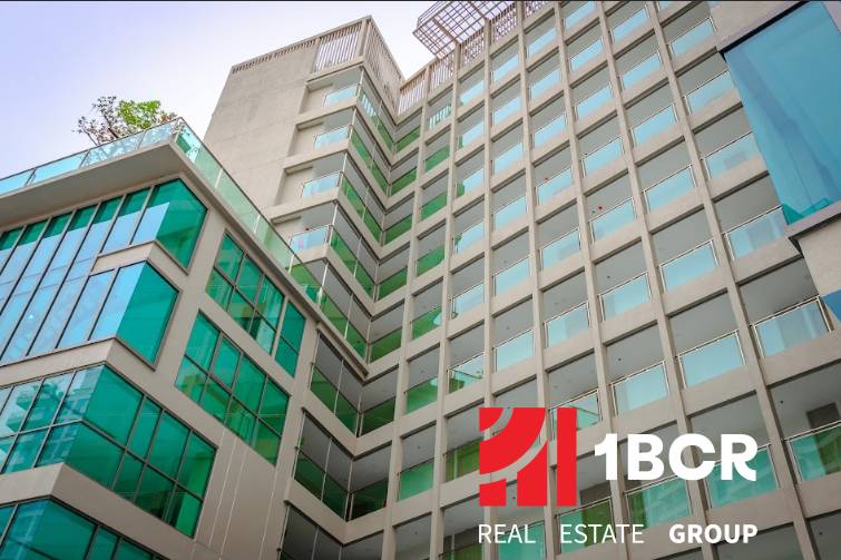 Construction of apartments in Pattaya with a glass facade and balconies in a modern design.