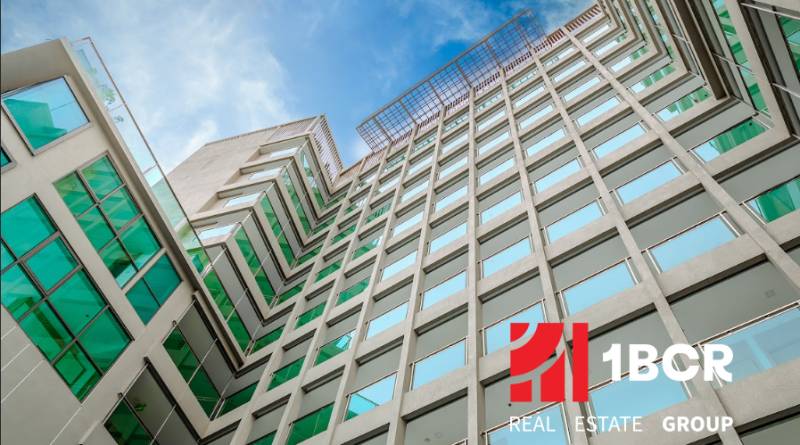 Apartment construction in Pattaya: a modern building with glass windows under an azure sky.