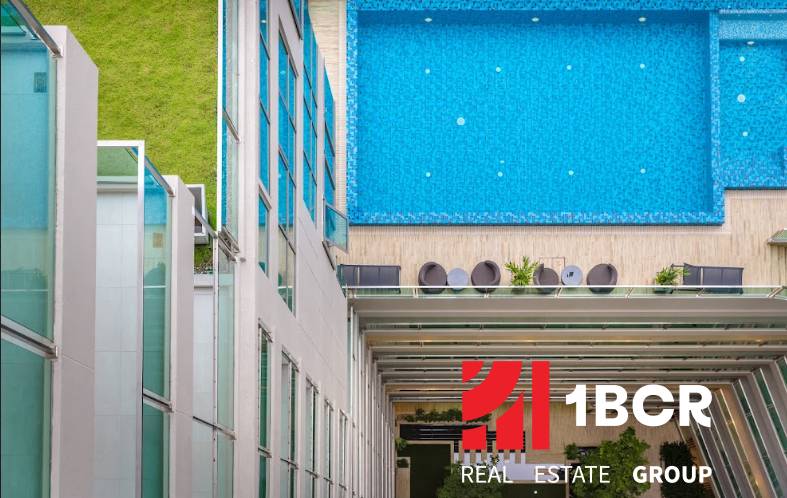 A rooftop pool, surrounded by a building and greenery, Apartment construction in Pattaya.