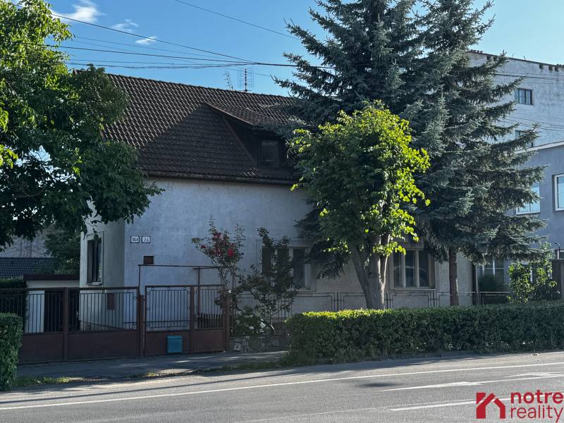 A family house in Lučenec surrounded by trees and a hedge, with access from the main street.