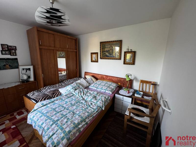 A bedroom in a family house with a wardrobe, a bed, and wall paintings.