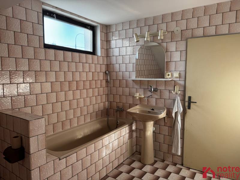 A family house bathroom with a bathtub and a sink, tiled.
