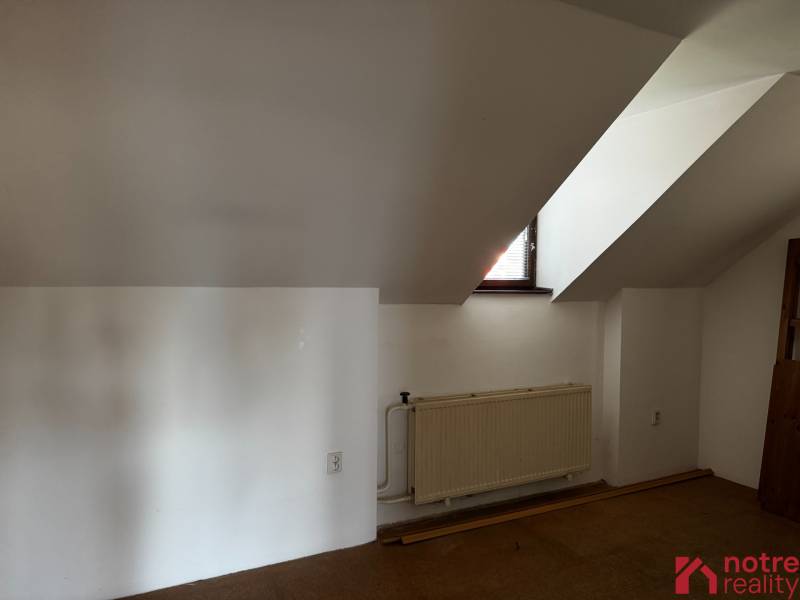 Attic room with a window and a radiator in a family house.