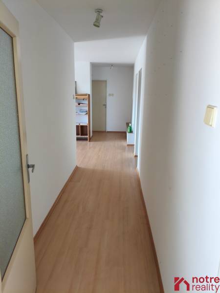 A hallway with a wooden floor and white walls leading to a door in a family house.