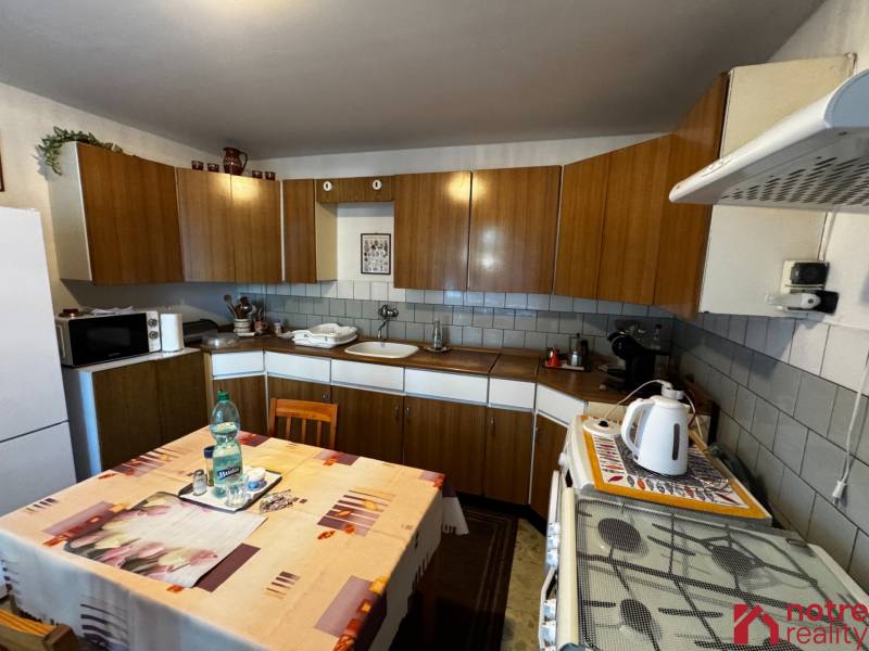A kitchen in a family house with a wooden cabinet and a dining table.