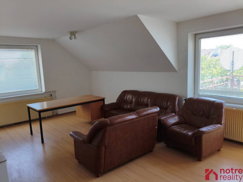 Living room with leather armchairs and a table in a family house, with large windows and blinds.