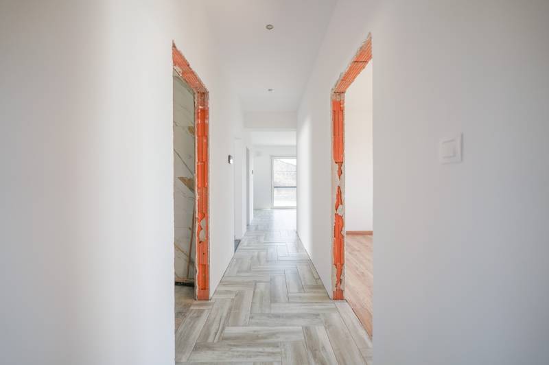 A hallway in a family house with tiles and unfinished door frames.