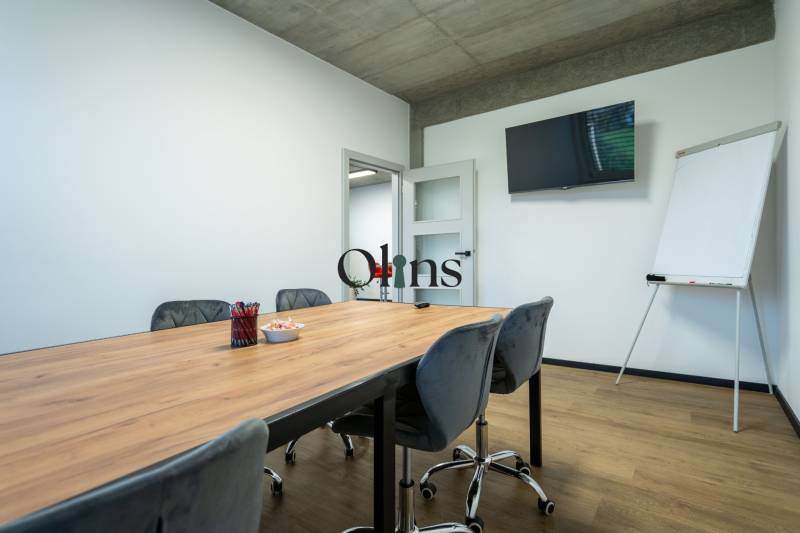 Offices with a wooden table, chairs, a board, and a television.