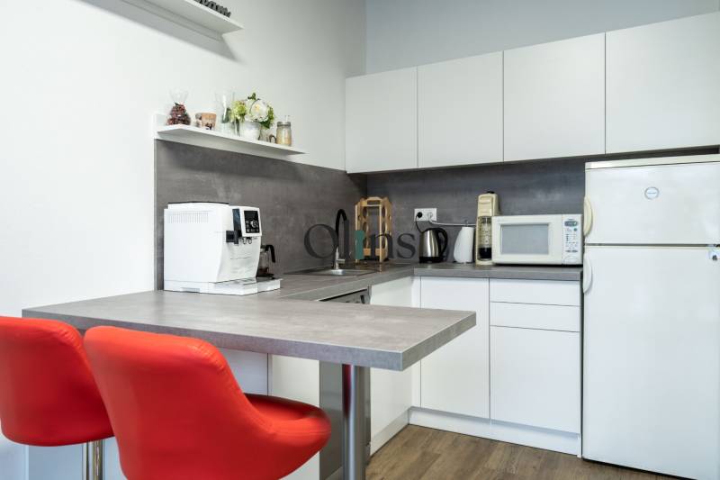 A kitchenette in the office with appliances and red chairs.