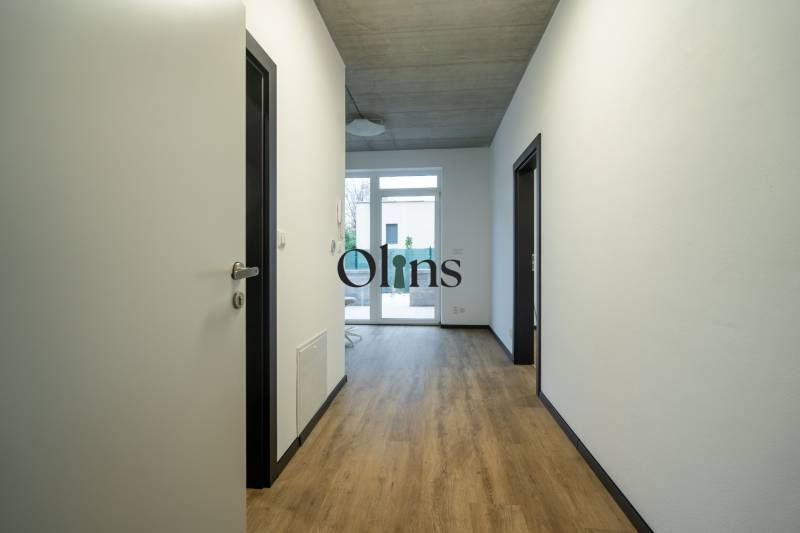 A hallway in offices with a parquet floor and a large window at the end of the room.