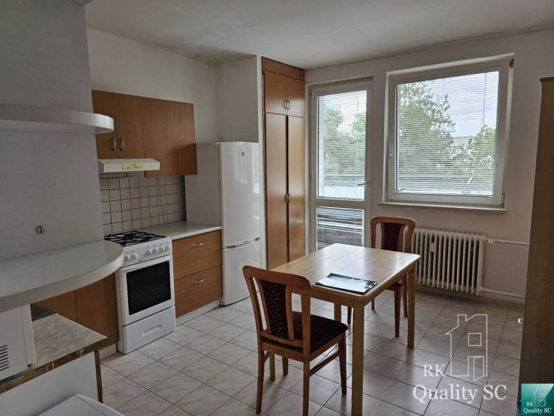 The kitchen in a 2-room apartment with a kitchen unit, table, and chairs.