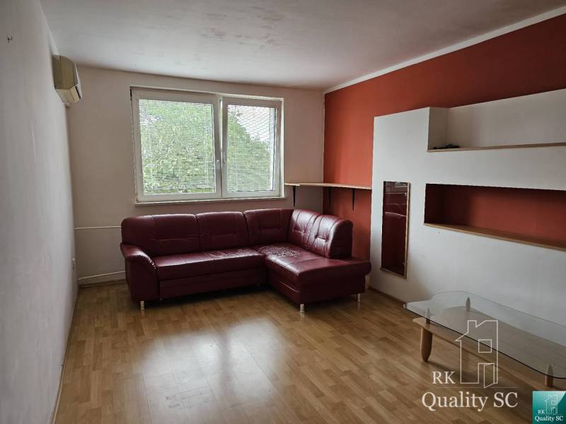 Living room with a corner sofa and a glass table in a 2-room apartment.