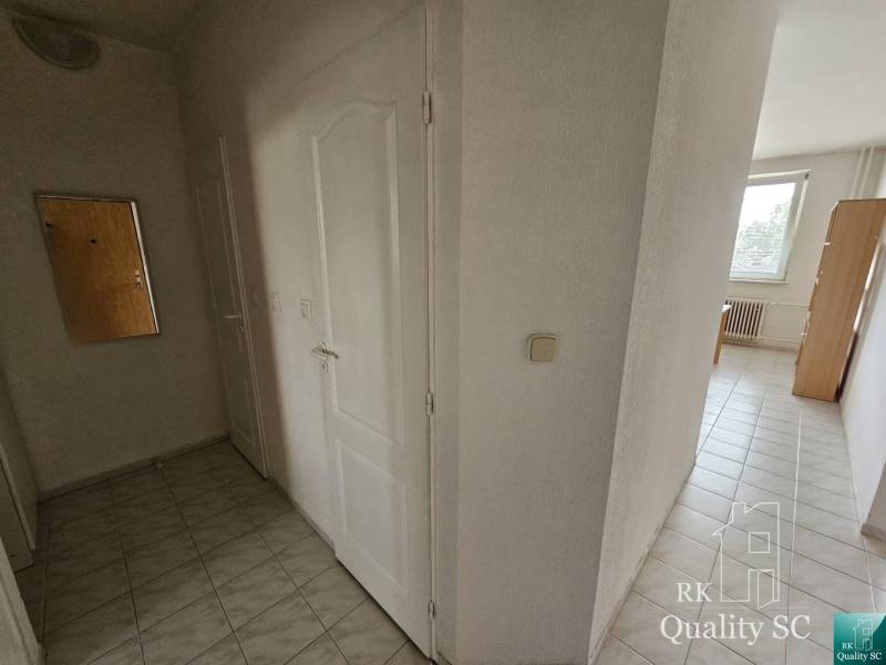 A hallway with light tiles and white doors in a 2-room apartment.