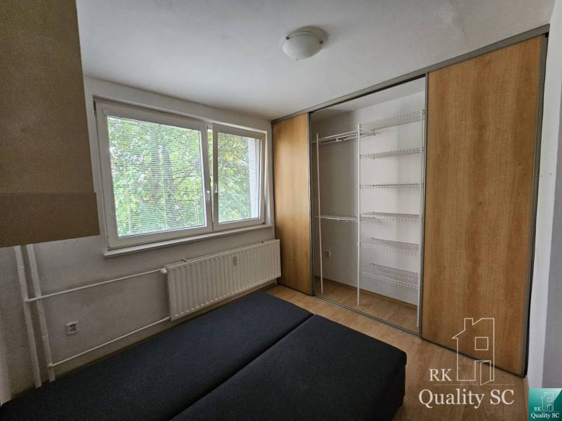 Bedroom in a 2-room apartment with a large built-in wardrobe and a radiator under the window.