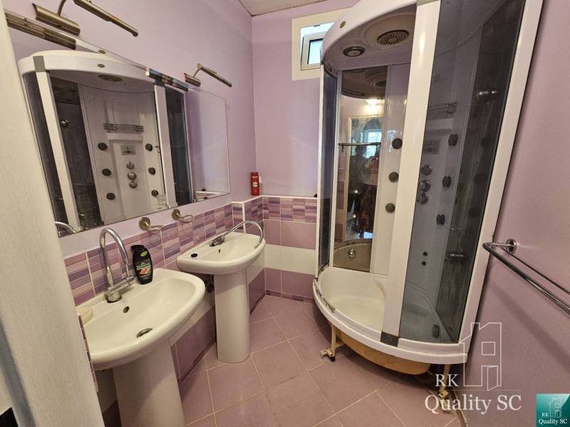A bathroom in a 2-room apartment with two sinks and a hydromassage shower.