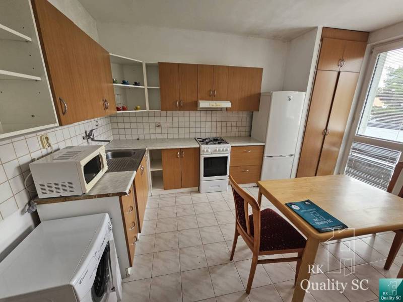 A kitchen in a 2-room apartment with wooden cabinets and a dining table.