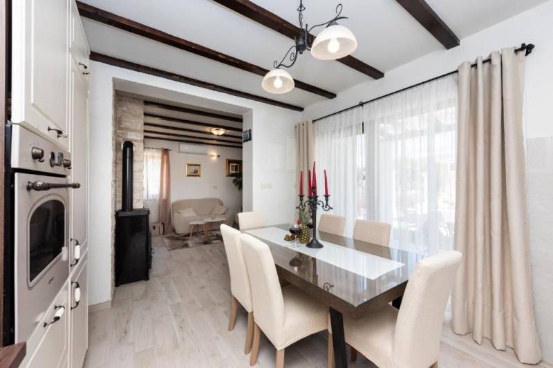 A dining room in a family house with a glass wall and wooden beams.