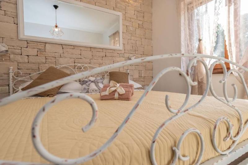 A bedroom in a family house with a decorated metal bed and a brick wall.