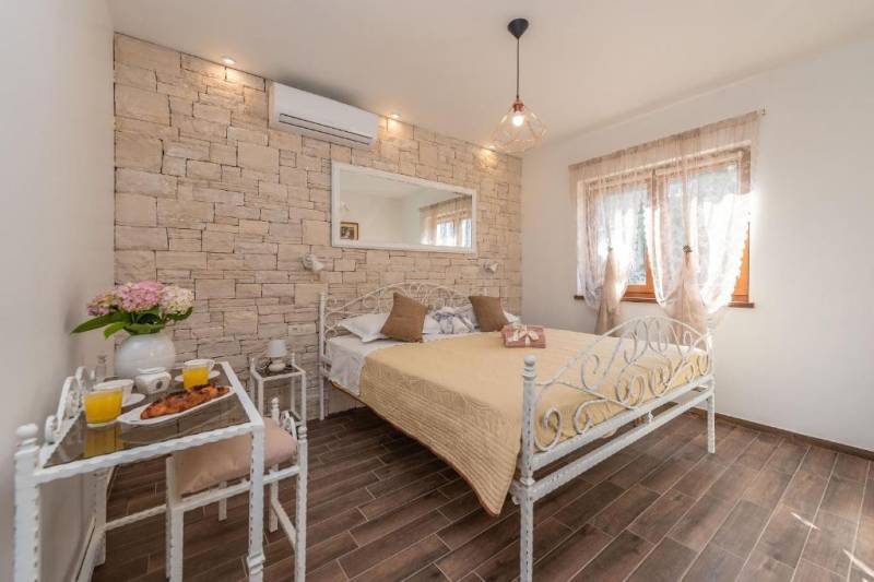 Bedroom with a stone wall, metal bed, and a table with drinks in a family house.