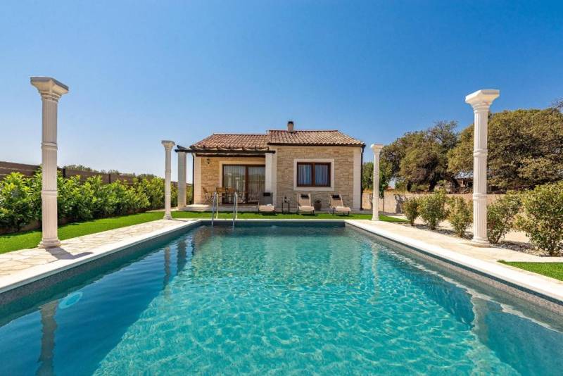 A family house in Bibinje with a pool, columns, and surrounding greenery.