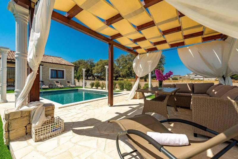 A terrace in a family house in Bibinje with a swimming pool and rattan furniture.