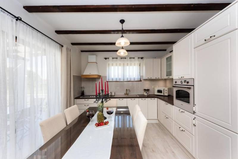 A kitchen in a family house with a dining table and candlesticks on a white table runner.