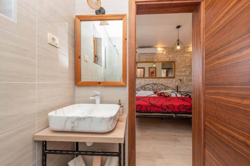 Bathroom with a sink, mirror, and a view into the bedroom in a family house.
