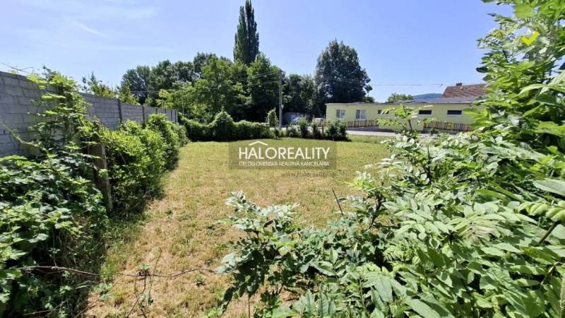 Plots - housing in Smolenice. Grassy area surrounded by a fence and greenery.