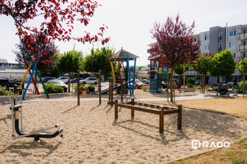 A children's playground in Trenčín with colorful climbing frames and trees, suitable for family time.