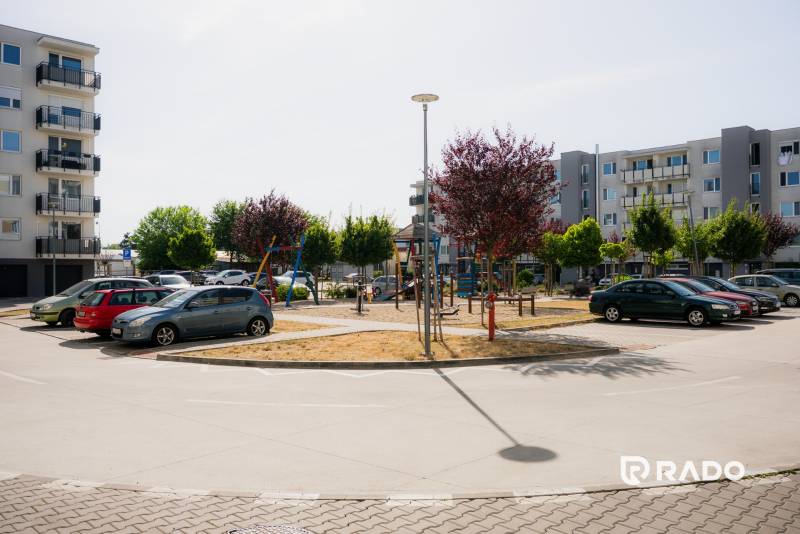 Parking lot and modern apartment buildings in Trenčín with a children's playground.