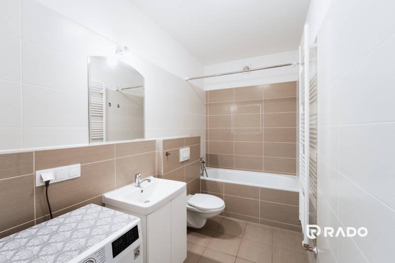 Bathroom with a shower, sink, and washing machine in a 2-room apartment.