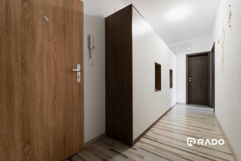 Narrow hallway corridors with wooden and white cabinets in a 2-room apartment.