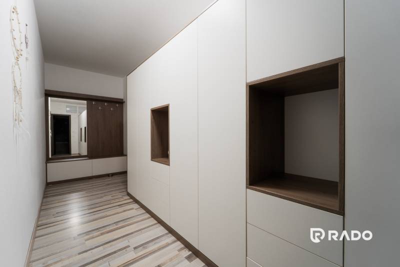 An entrance hallway in a 2-room apartment with white and wooden cabinets.