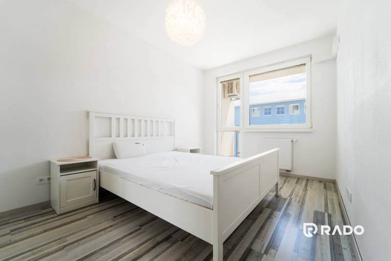 A bright bedroom with a white bed and furniture in a two-room apartment.