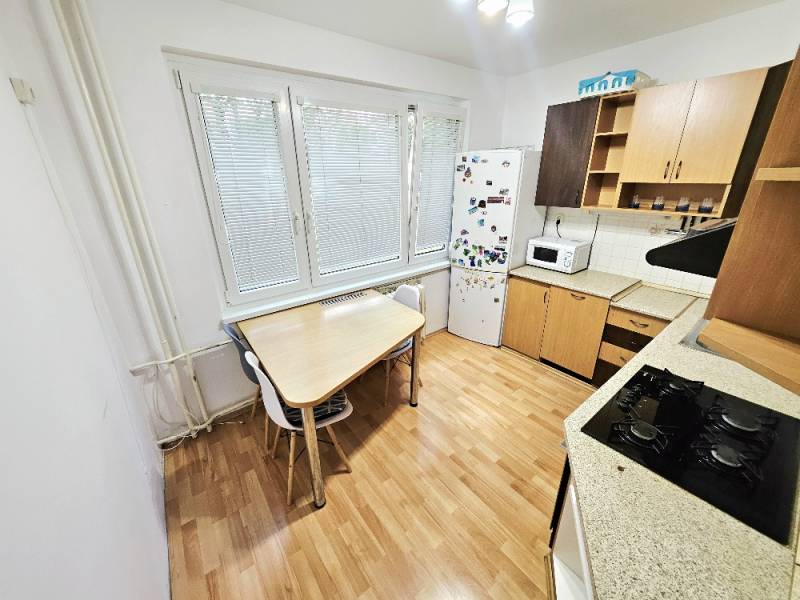 A kitchen with a stove, refrigerator, and table in a 3-room apartment.