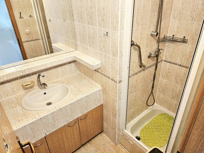 Bathroom with a sink, shower corner, and tiling in a 3-room apartment.