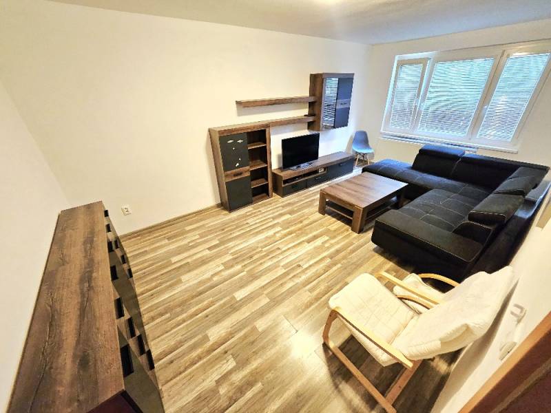 Living room in a 3-room apartment with a dark sofa and wooden furniture.
