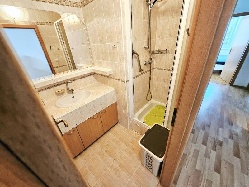 Bathroom with a shower in a 3-room apartment, light tiles and a mirror.
