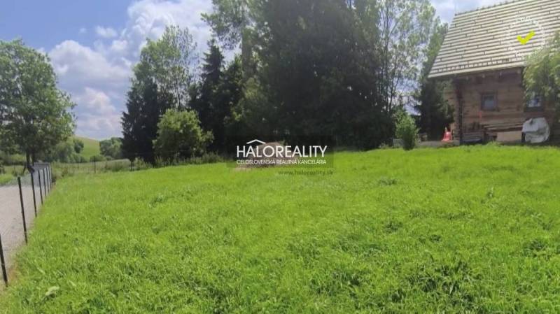 A plot in Malatíny with a grassy area and a wooden house, ideal for living.