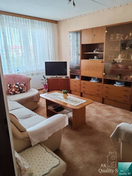 Living room with a sofa, television, and wooden cabinet in a three-room apartment.