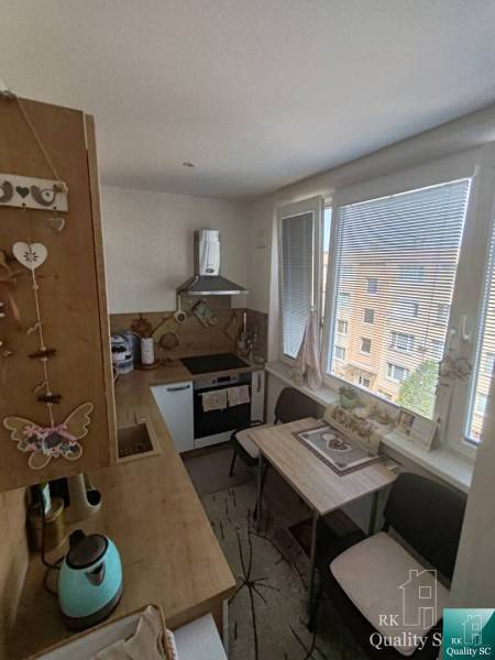 A kitchen in a 3-room apartment with a wooden cabinet, dining table, and appliances.
