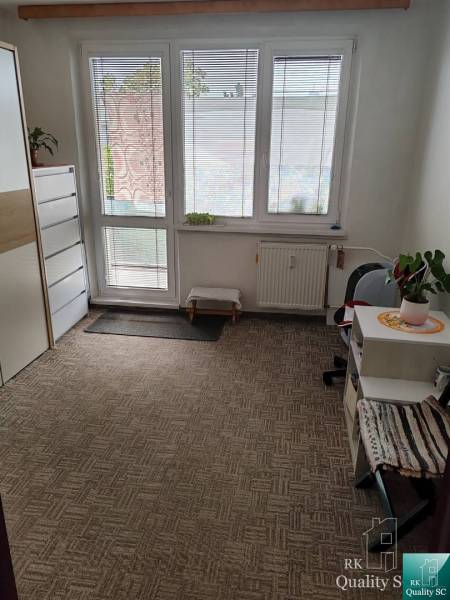 A room in a 3-room apartment with a carpet, furniture, and large windows with a view.