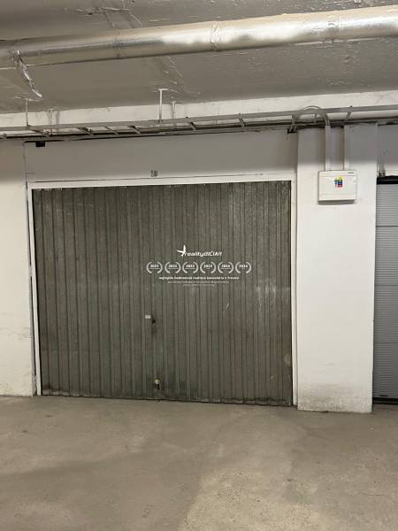 Metal gate in the garage with piping and an electrical panel on the wall.