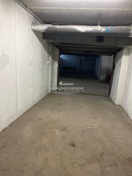 A view of the internal access corridor in the garages with visible pipes and ceiling.