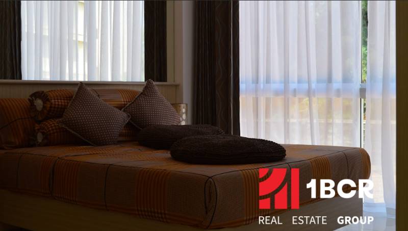 A bed with brown bedding and pillows in a 2-room apartment.