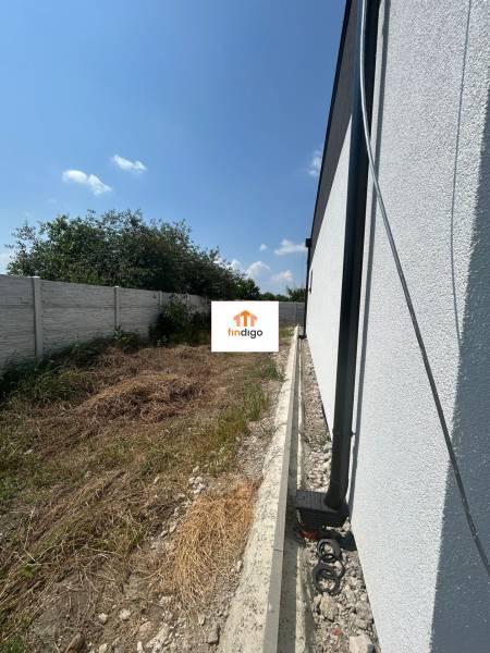 A family house in Žihárec with a garden, fencing, and a blue sky in the background.